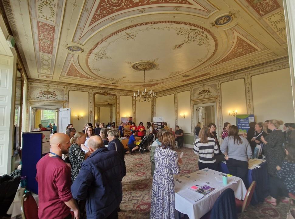 People gathered round tables and stalls looking at information and talking to each other