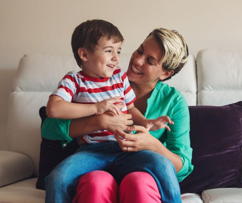 A foster carer is holding a young child and they are smiling at each other