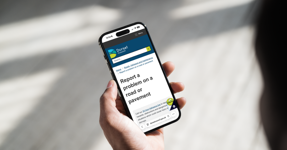 A mobile phone and on screen it says 'report a highways issue'