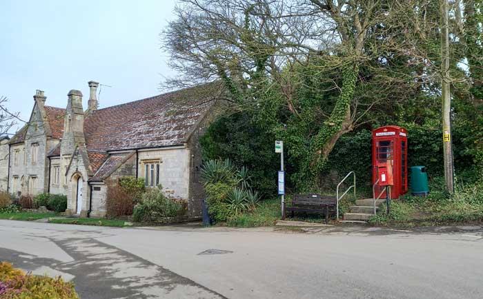 A church in a village next to a tree and a red telephone box