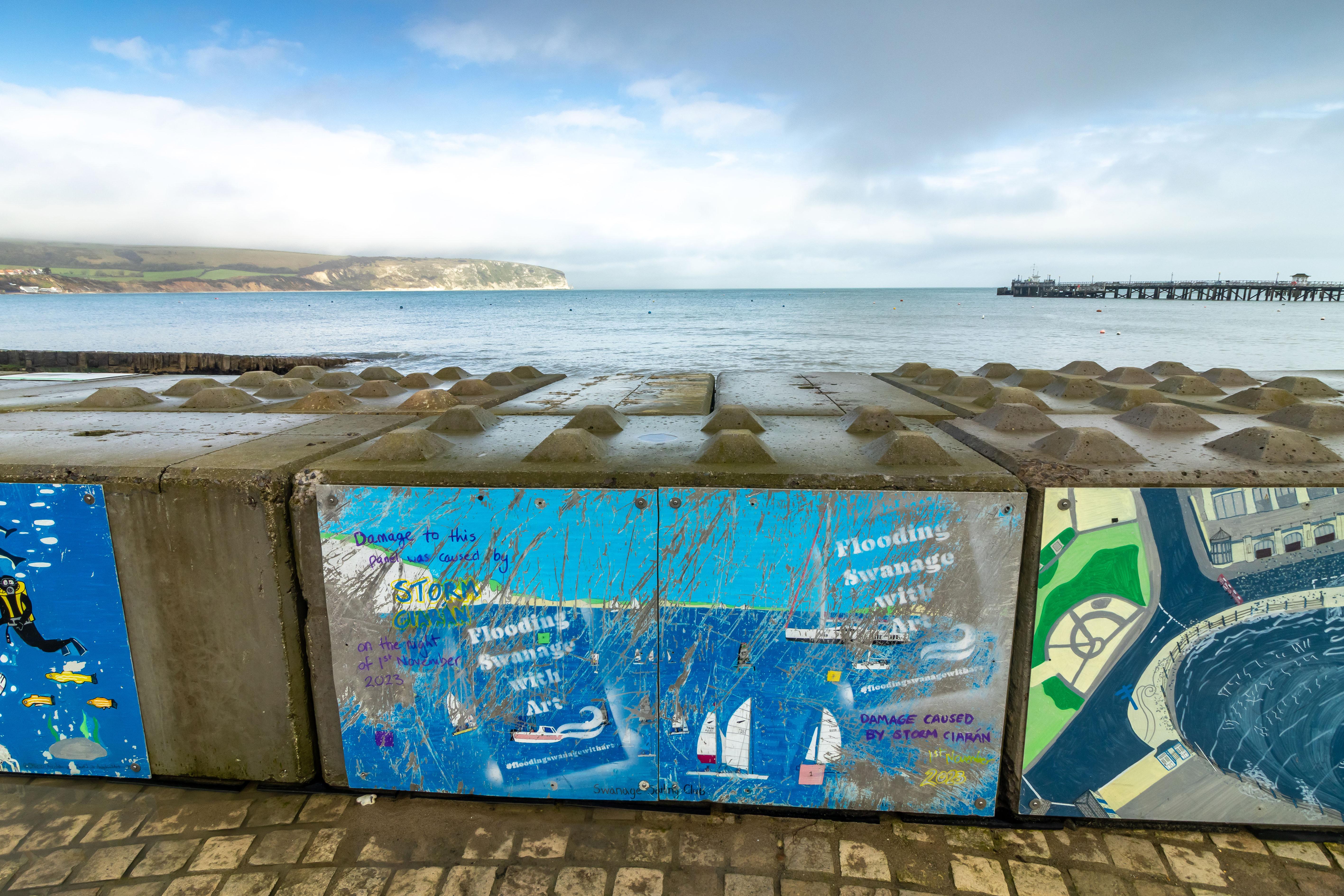 Concrete blocks with artist's paintings of the sea on them, with the real sea in the back