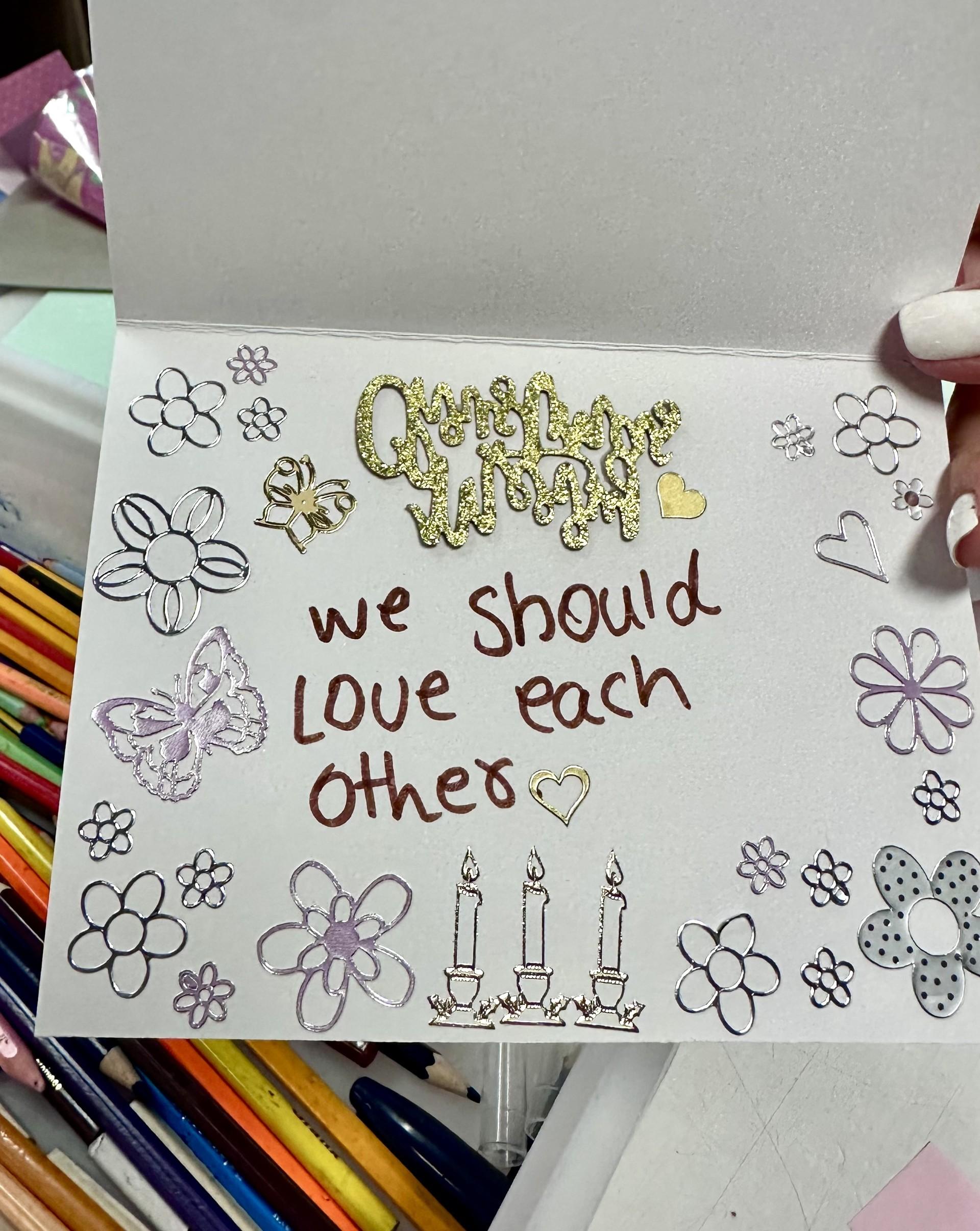 art from a refugee child, a card saying we should love each other with drawings of candles and hearts