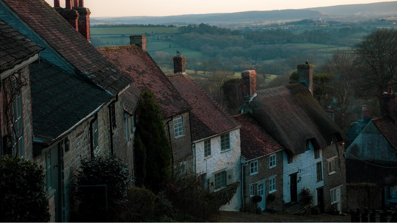 Shaftesbury's Gold Hill. A steep cobbled street lined with pretty cottages some of which have thatched roofs. Other roofs are tiled. This street featured in the famous Hovis advert.