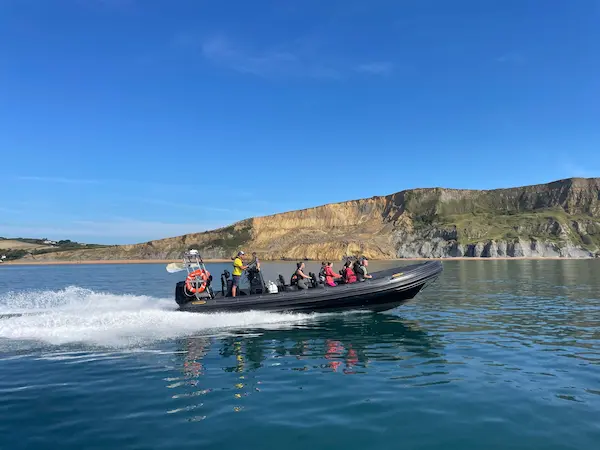Side on picture of a rigid inflatable boat riding along the sea