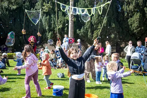 Children and families making giant bubbles at an outdoor community event