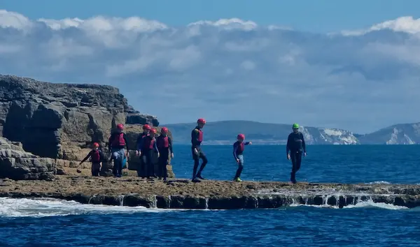 Group of people just about to jump off some rocks into the sea