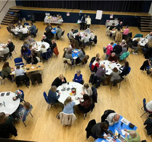 A large room with round tables surrounded by people engaged in conversation or activities