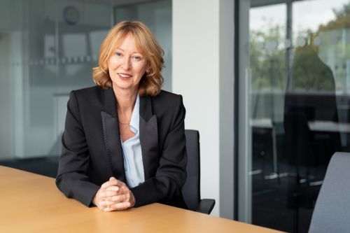 Catherine Howe sat at a desk smiling, in County Hall, Dorchester