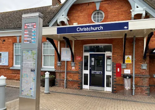Entrance to Christchurch railway station, showing the station building, main doorway and a timetable and information display outside.