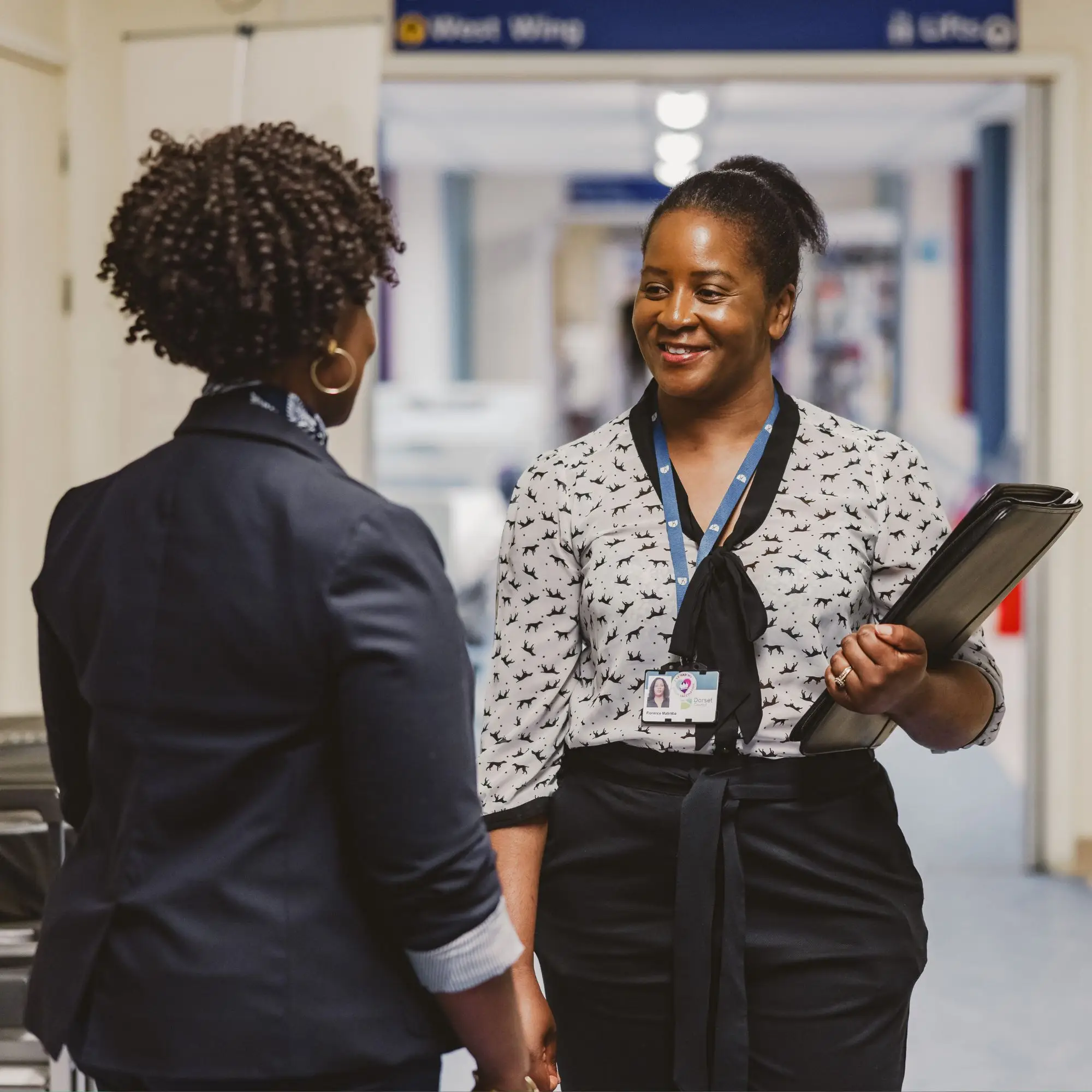 Two colleagues in conversation within a hospital corridor
