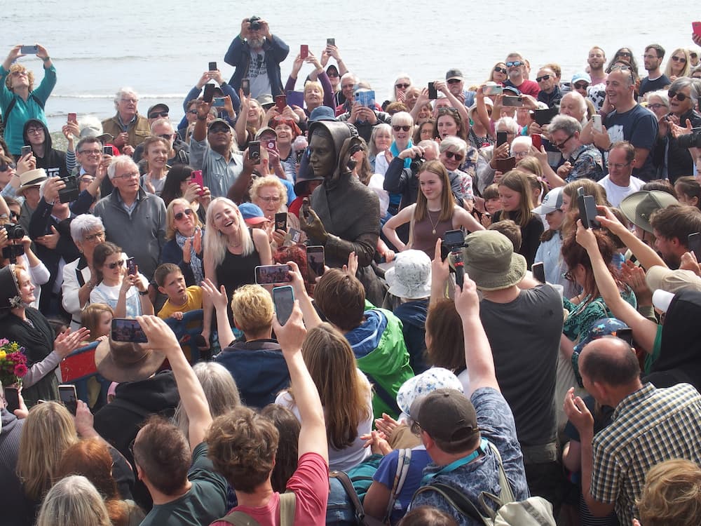 A crowd of people photographing the new statue of Mary Anning at Lyme Regis