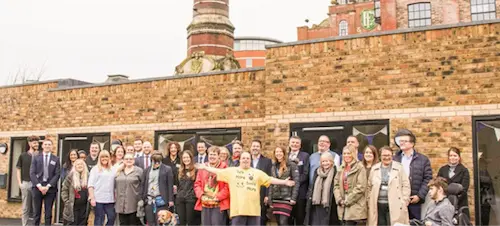 A group of people standing in front of a building and looking towards the camera