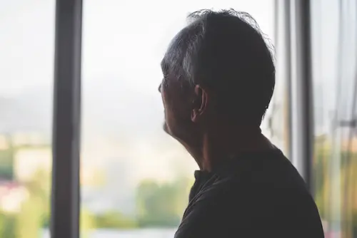 Sillhouette of a man looking through a window into the distance