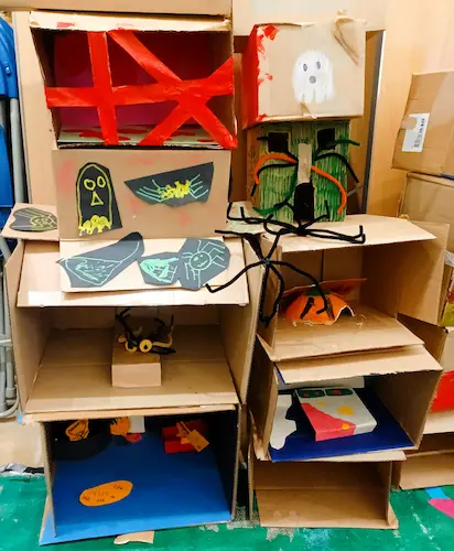 Cardboard model decorated with handmade spiders, webs and Halloween-themed artwork created during a craft activity.