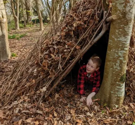 Child within a shelter built within the woods