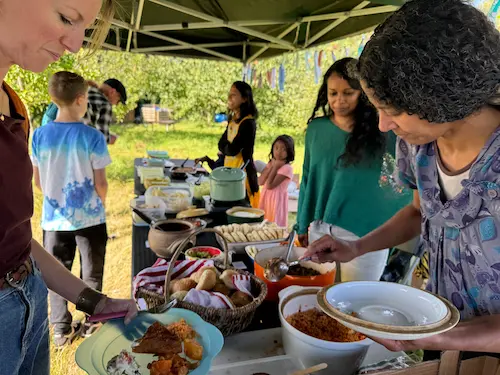 Community food event with people serving and sharing food outdoors.