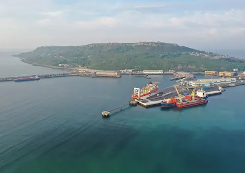 Aerial view of Portland Port with cargo ships, docks, warehouses and quaysides, set against the coastline and cliffs of the Isle of Portland.