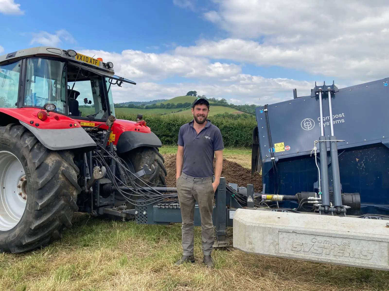 Tom Gregory sood beside a tractor with green fields and compost behind