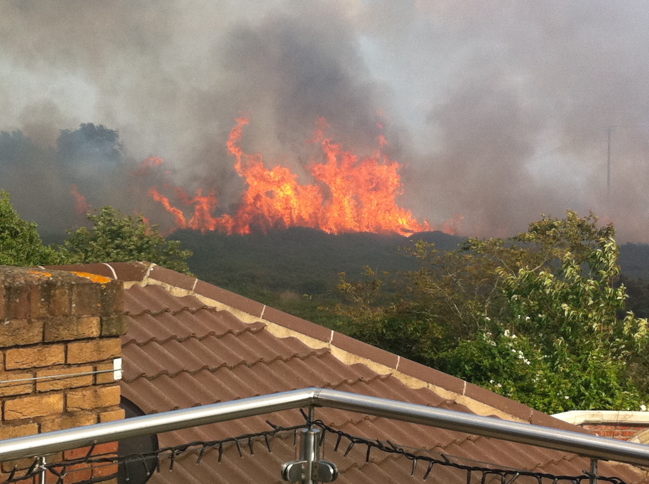 Heath fire in the distance with a house roof bottom left