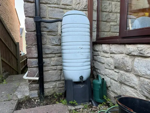 Water butt against a home with a stone wall