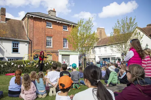 Children watching a street performance in a town square during a community event.