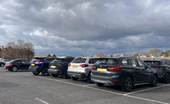 a row of black and silver cars parked in a car park