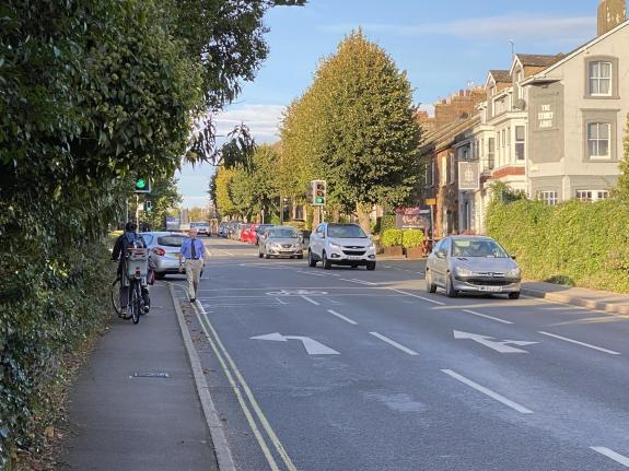 A busy road with cars and a person walking on the road