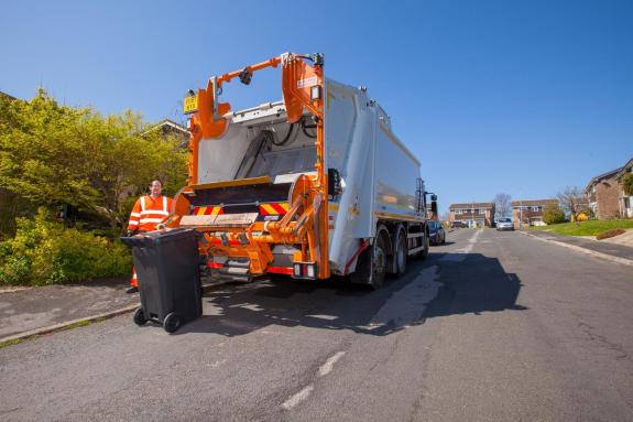 Bin being emptied into waste collection lorry on residential street