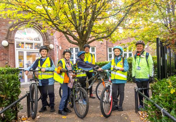 Four school children with bikes plus two adults wearing cycle helmets
