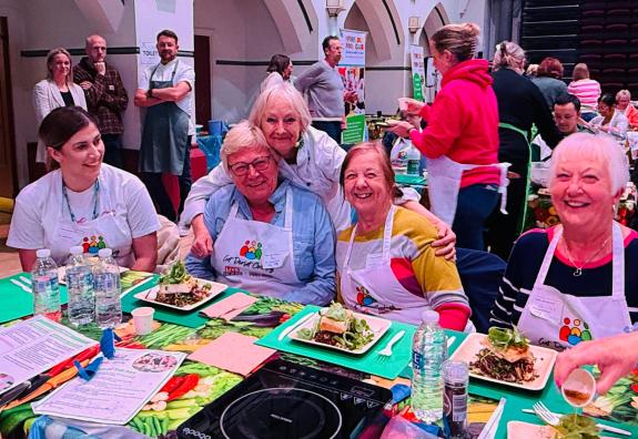 A group of people smiling at the camera with their plates of prepared food in front of them