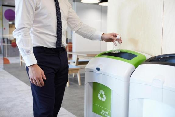 Someone putting something in a recycling bin