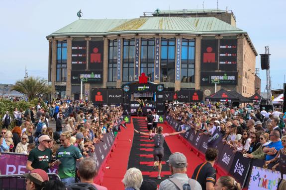 Runners on the red carpet approaching Weymouth Pavilion surrounded by crowds of people